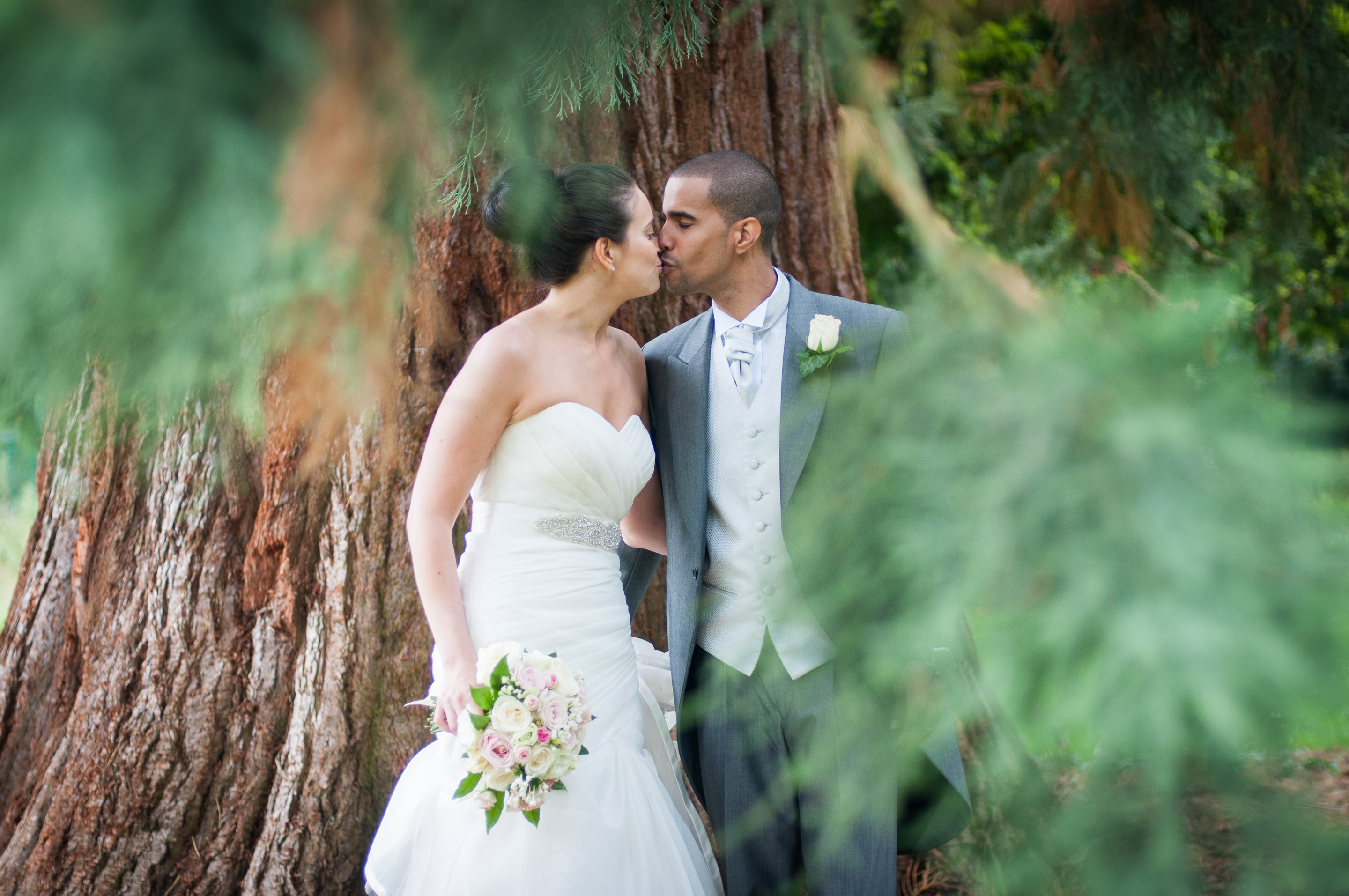 Bride and groom photographed through the trees