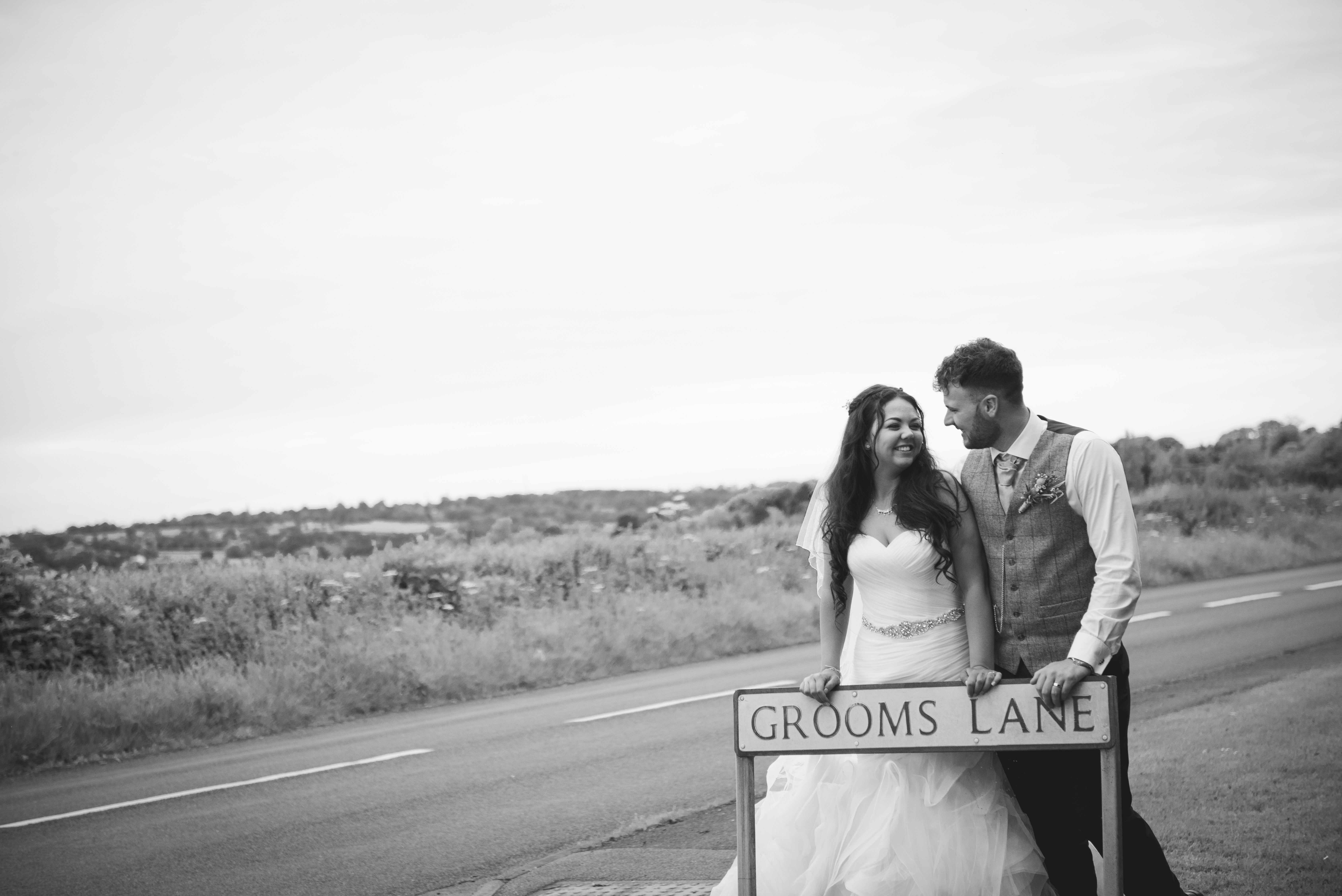 Grooms lane, bride and groom pose at the entrance to their venue